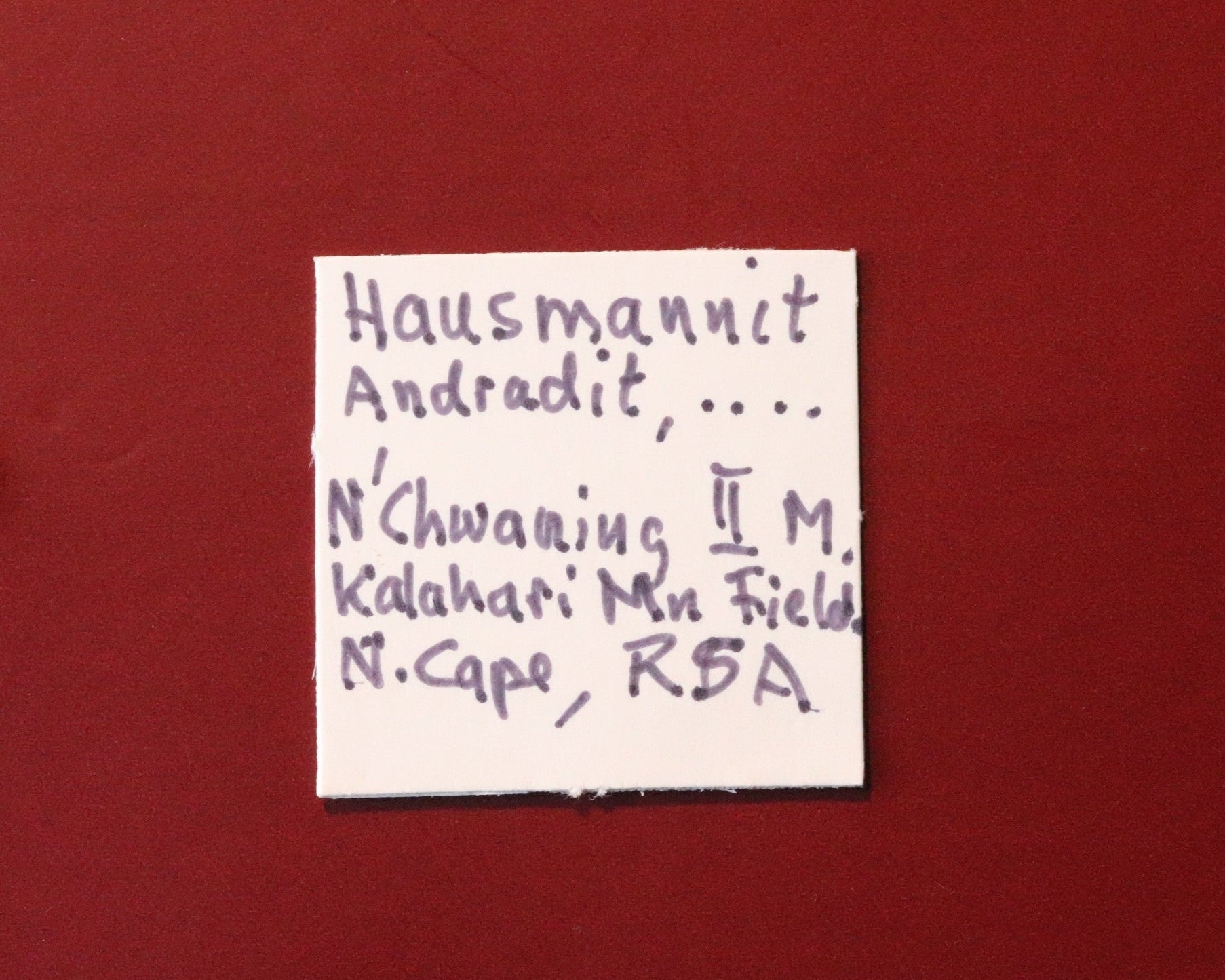 Front of label for Hausmannite with Andradite and possibly Bementite from N'Chwaning II, Kalahari Manganese Fields, South Africa